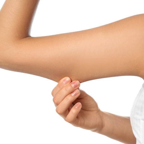 Young woman drawing attention to arm on white background, closeup. Plastic surgery concept